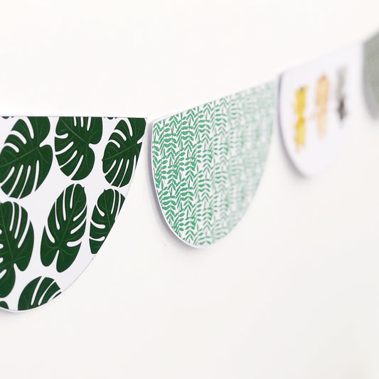Scalloped Bunting shape with  green leaf patterns displayed on a white wall 