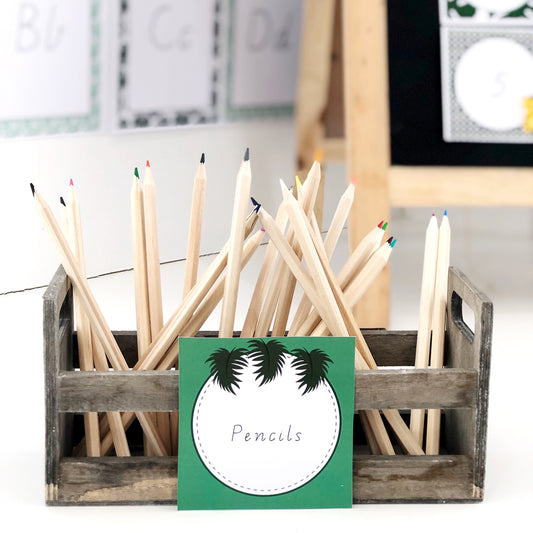 Pencils displayed in wooden caddy with a green classroom label featuring jungle leaves. 