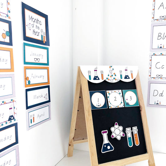 Various classroom educational charts displayed on a white wall and blackboard in a science theme. 