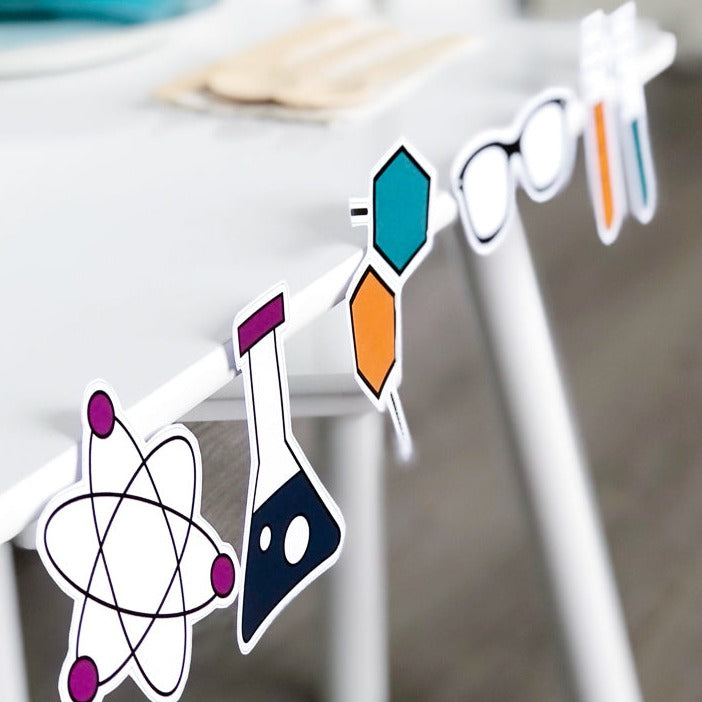 A set of colorful science-themed party decorations, including shapes like atoms, molecules, and spectacles, displayed on a white surface.