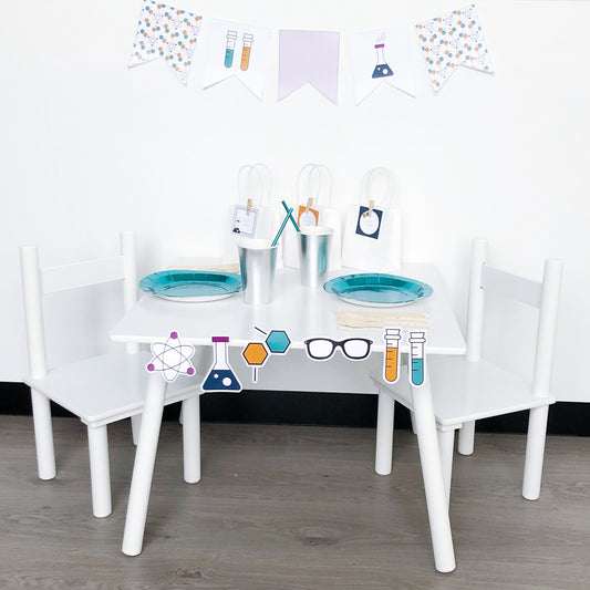 Science theme party table set up with plates, cups, bunting flag, party bags and cut out shapes. 