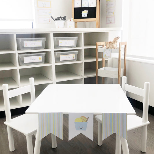 Pastel sorbet theme classroom decor on display with a white table and chairs. 