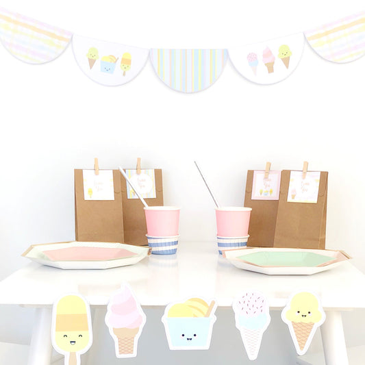Ice cream party table set up with bunting flags and party bags. Cute little sorbet graphics are on the front of a white table. 
